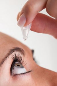 Woman treating dry eye with eye drops
