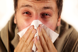 Man with allergies blowing nose